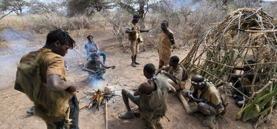 Hadzabe tribe huddling around a fire in the morning